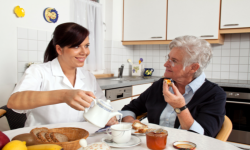 care giver and old woman eating